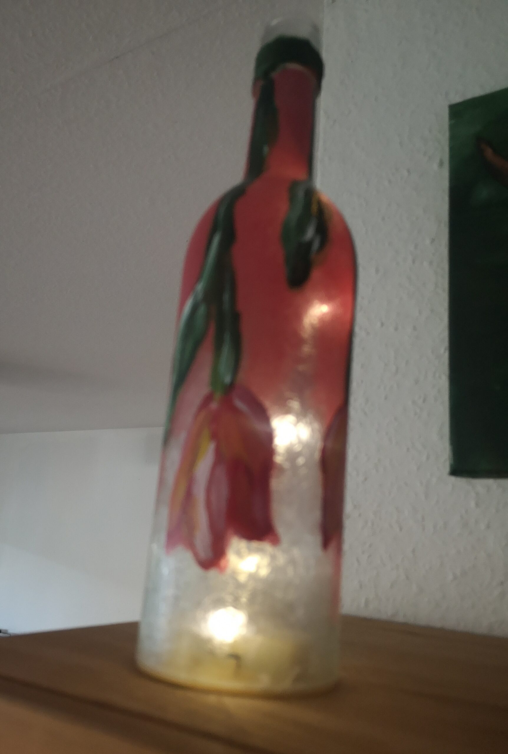 Bild einer beleuchteten Flasche, die mit hängenden Tulpen bemalt ist