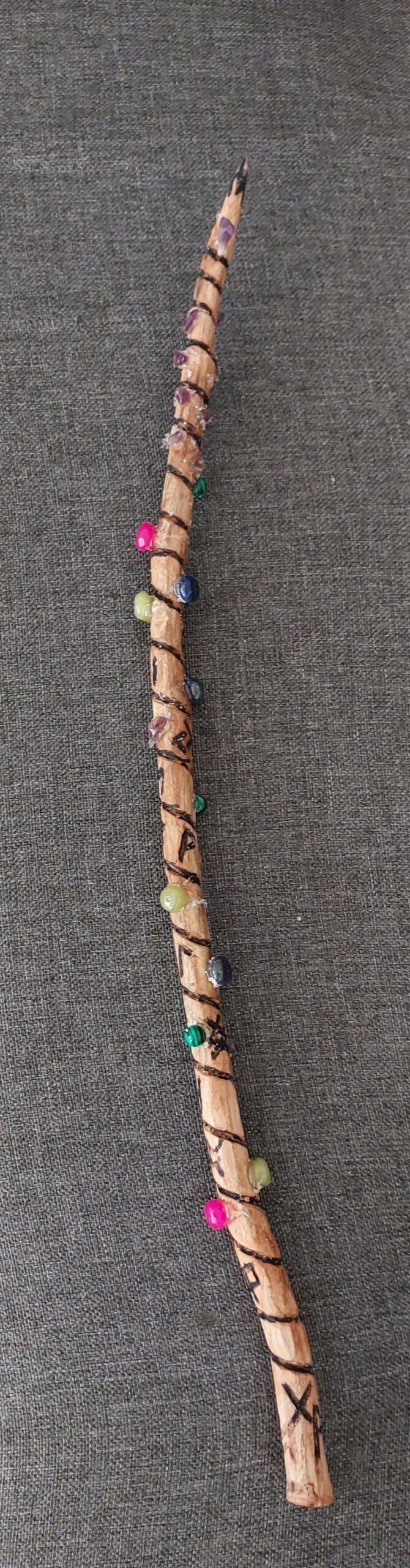 Bild eines aus Holz geschnitzten Zauberstabes mit eingeschnitzten Runen und angebrachten Halbedelsteinen
