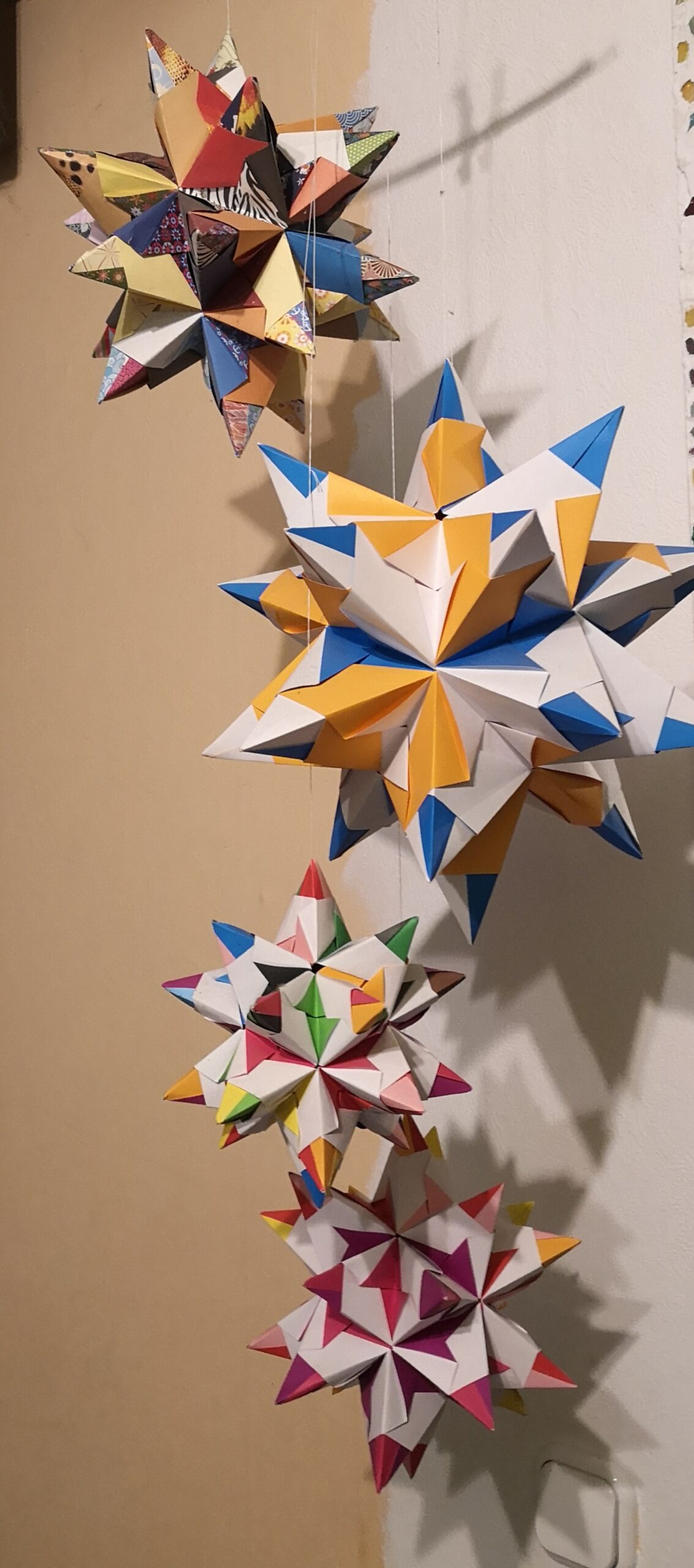 Bild verschiedengroßer Origami-Sterne an einem Mobile hängend