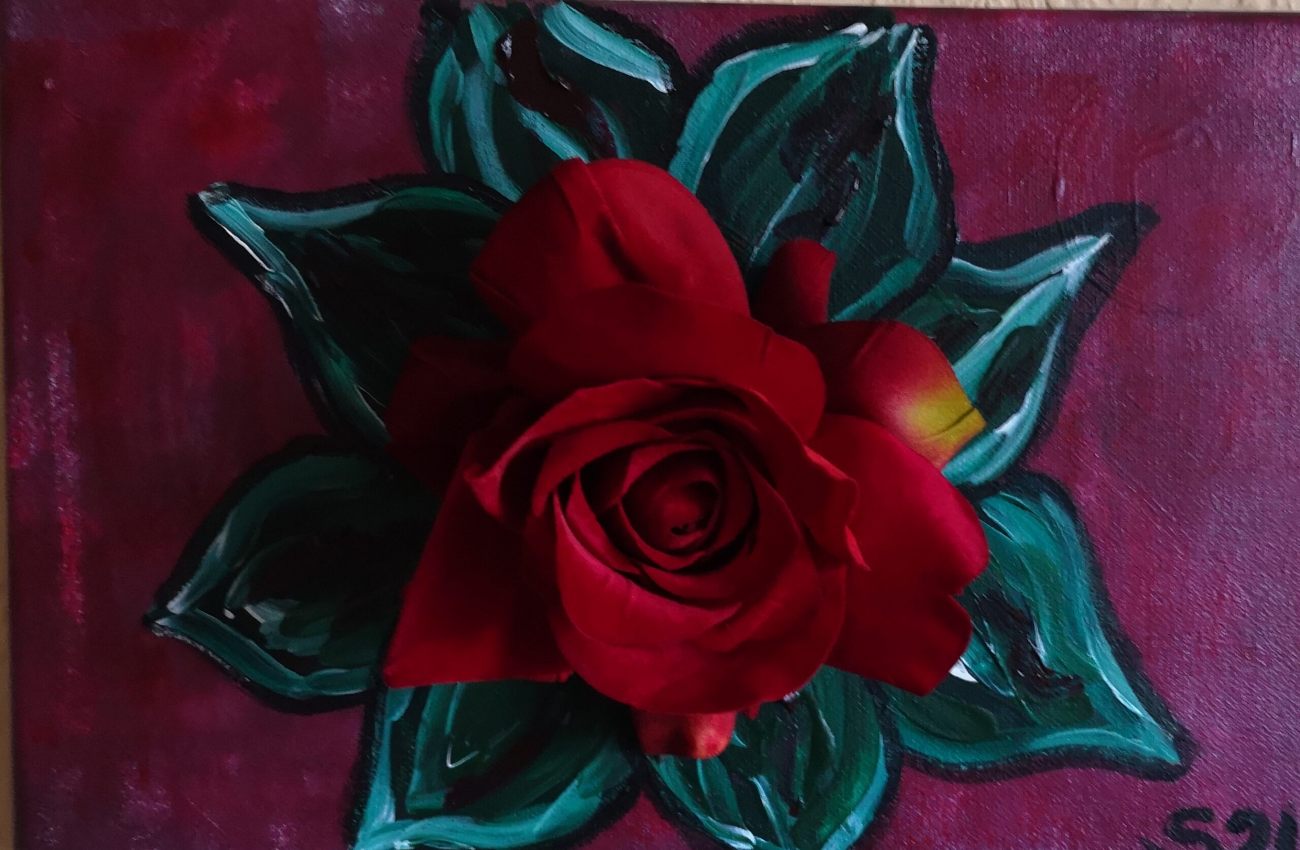 Bild mit Blätern und künstlicher Rosenblüte in der Mitte